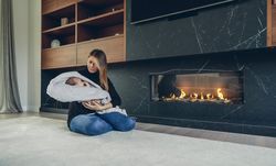 Mother hugging her baby in front of fireplace