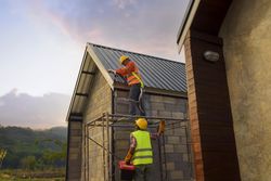 Two men with bump caps building a roof