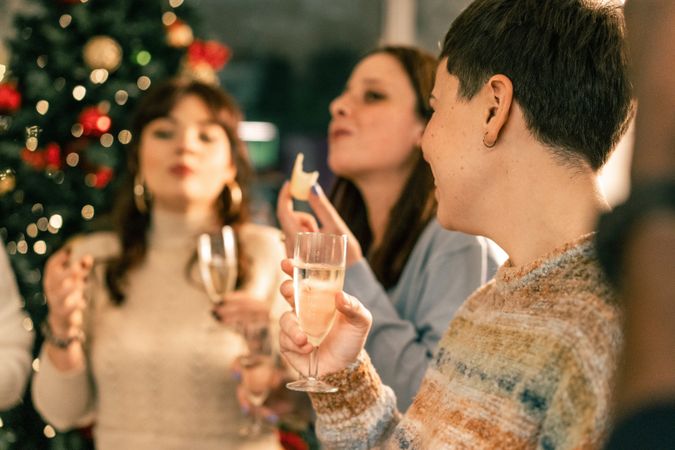 Group of happy friends laughing and toasting with champagne at a Christmas party.