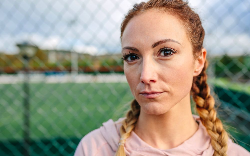 Serious young sportswoman with boxer braids looking camera