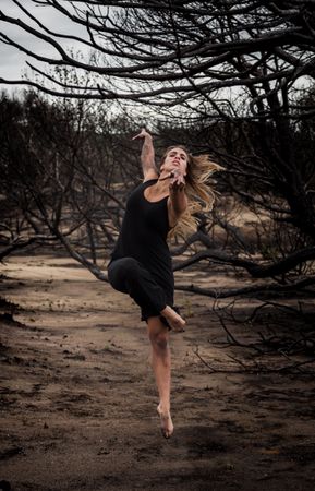 Woman dancing between dry trees