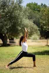 Arab woman doing Warrior yoga pose in nature