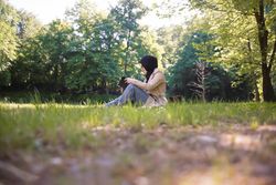 Woman in park with book surrounded by trees