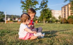 Baby girl and child playing sitting on a grass park