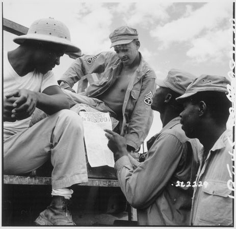 Black American soldiers reading “Victory in Europe” sign in World War II