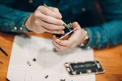 Cropped image of technician fixing smartphone's parts