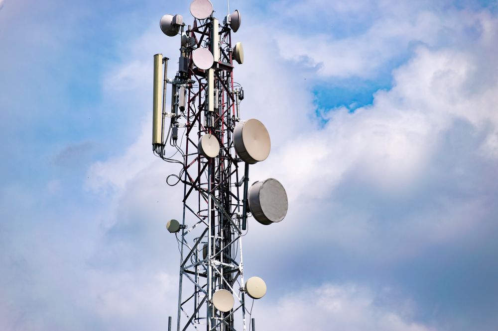 Telecommunication Antenna Tower Against a Blue Sky With Cloudy Background