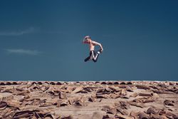 Strong active man jumping on roof while performing freestyle dance