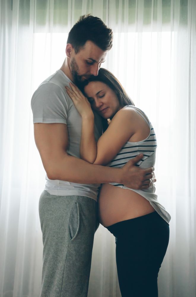 Pregnant woman embraced by her husband