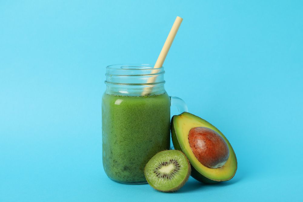 Smoothie, avocado and kiwi on blue background