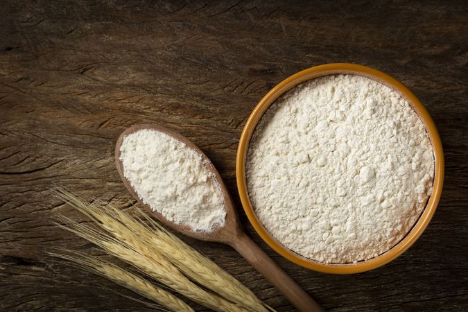 Bowl with wheat flour on the table.