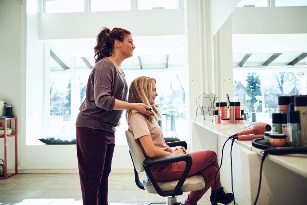 Side view of hairdresser showing client new haircut though reflection of mirror