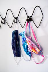 Pink and blue PPE masks hanging on coat rack