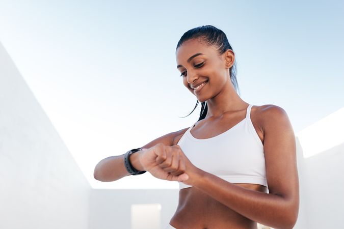Smiling fit woman checking watch