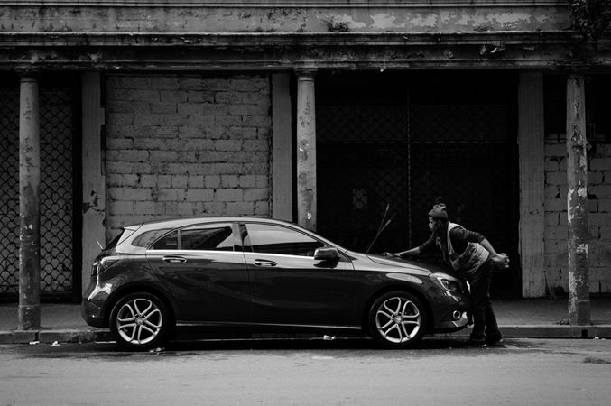 Grayscale photo of man wiping the car front