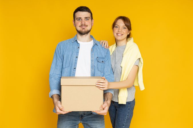 Moving concept, couple with box on yellow background