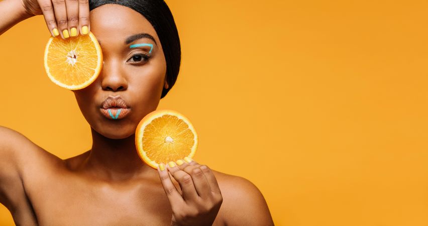 Young woman with artistic makeup and oranges in hand