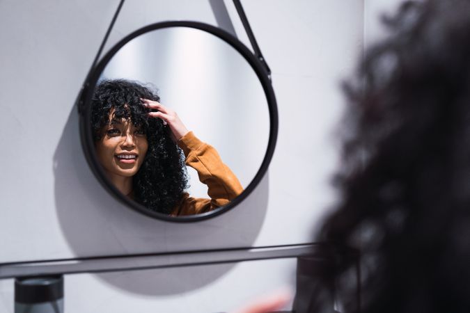 Smiling Black woman looking at mirror at home