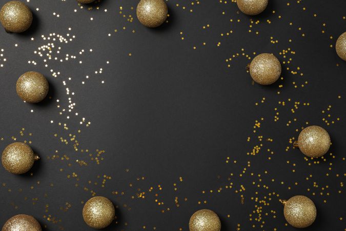 Christmas balls and glitter on dark background, top view