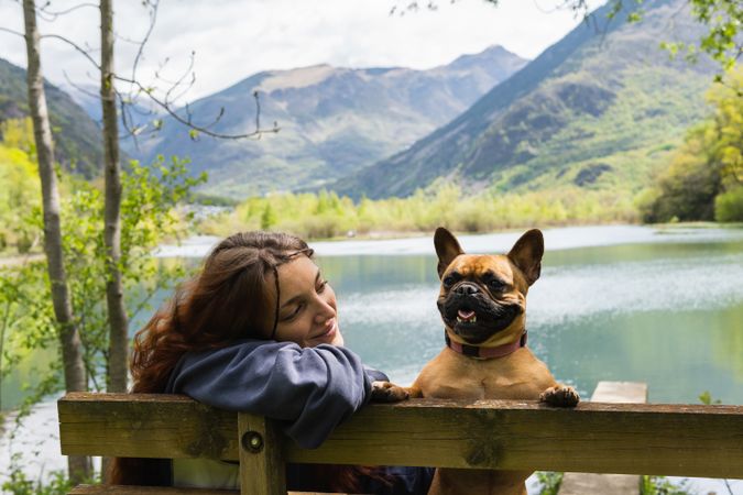 Female traveler with dog near lake in mountains