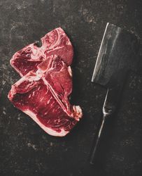 Two T-bone steaks with cleaver on butchers block