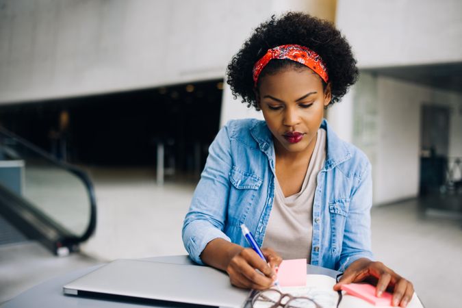 Woman writing notes at work in an open office