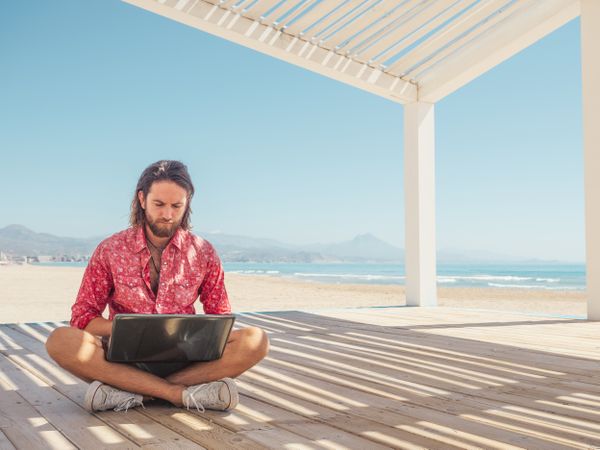 Man using laptop on beach
