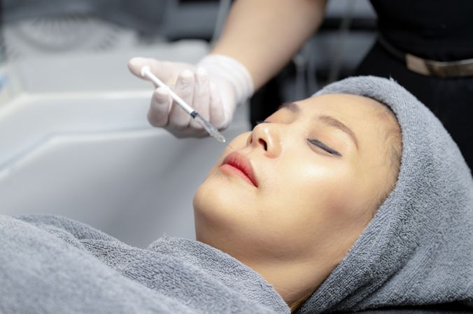 A young woman injects vitamins into her face in a beauty clinic.