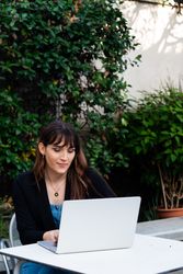 Transgender woman typing on a laptop outside