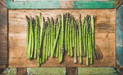 Asparagus lined up on wooden board with green trim