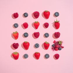 Row of multiple berries on pink background