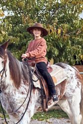 Boy in hat riding his brown mottled horse