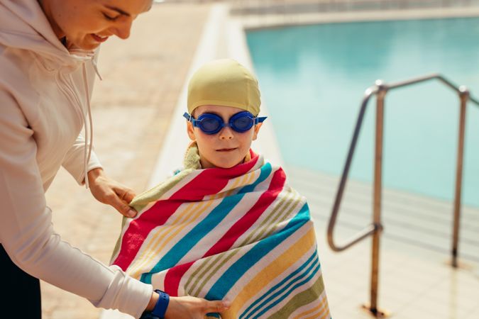 Woman wrapping towel on boy after swimming in the pool
