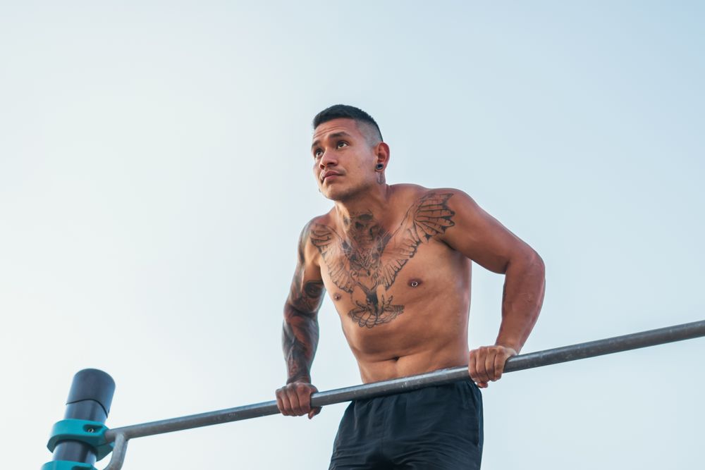 male athlete doing dips on a bar outdoors