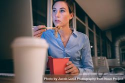 Businesswoman eating food sitting at her table while looking at the computer screen 5XVnKb