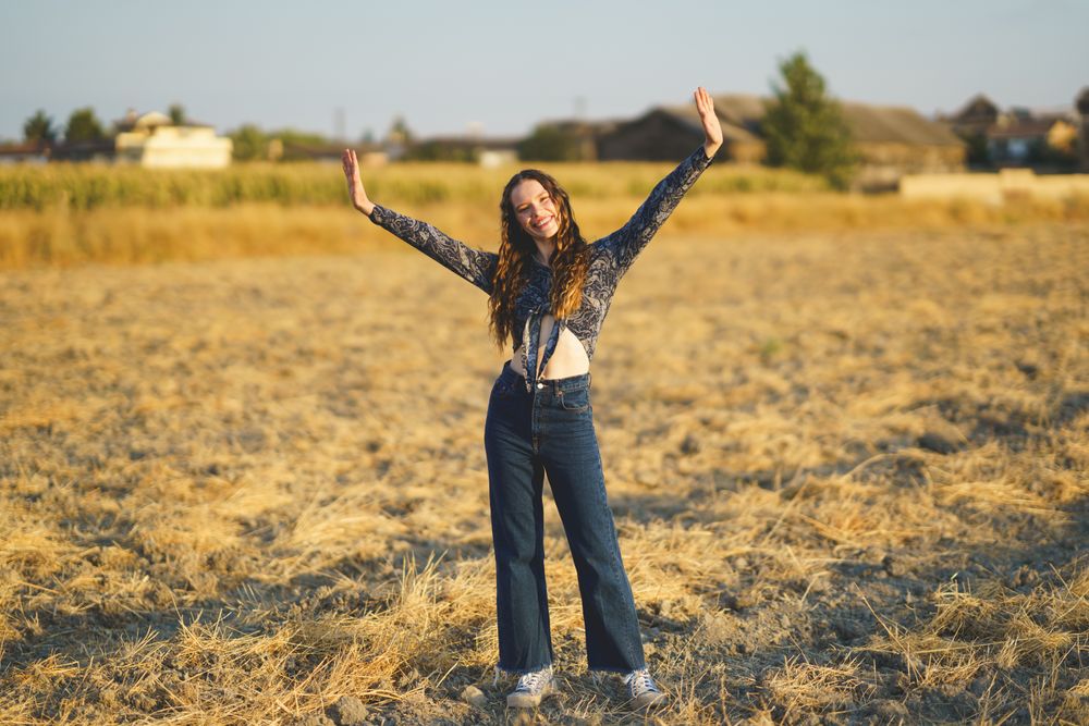 A Joyful Young Woman Dancing Happily in a Brightly Sunlit Field on a Beautiful Day