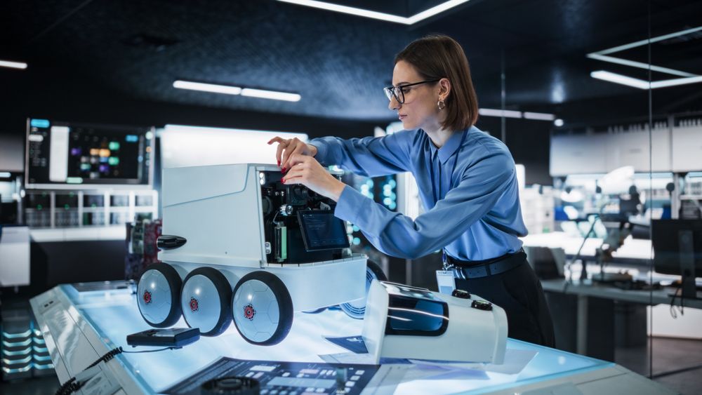 Portrait of a Female Technical Specialist Working in High Tech Research Laboratory with Modern Equipment: Female Adjusting Equipment on a Delivery Robot