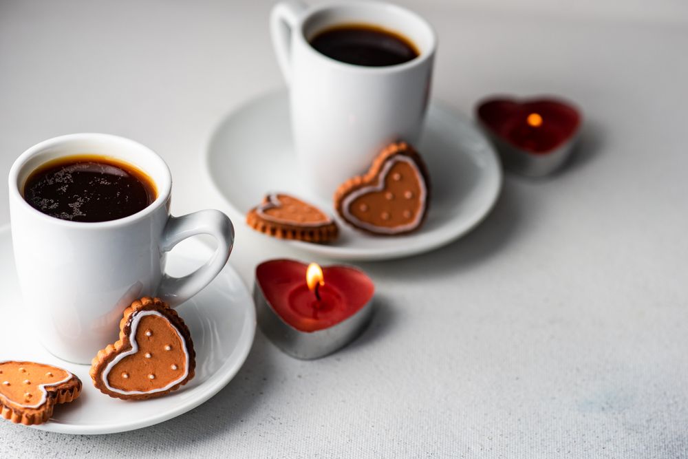 Two coffees with iced cookies and heart candles