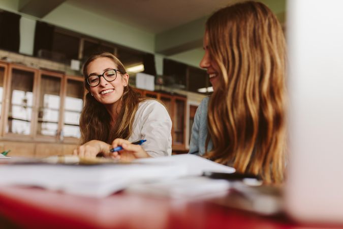 Smiling young teacher helping female student during her class