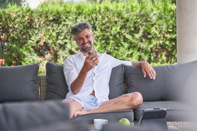 Adult man browsing mobile phone in backyard