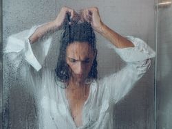 Despaired woman in wet shower cabin