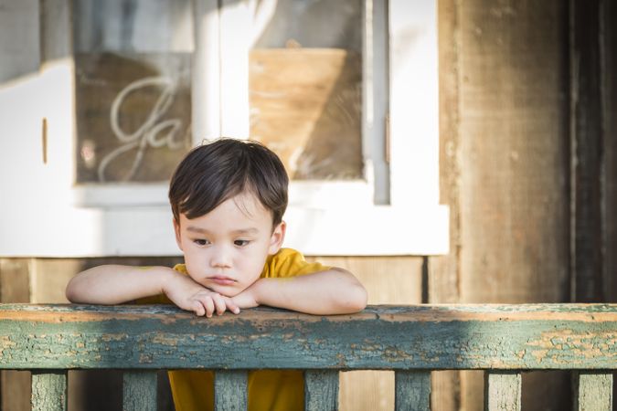 Melancholy Biracial Boy Leaning on Railing