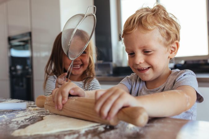 Little boy and girl preparing cookies on kitchen table
