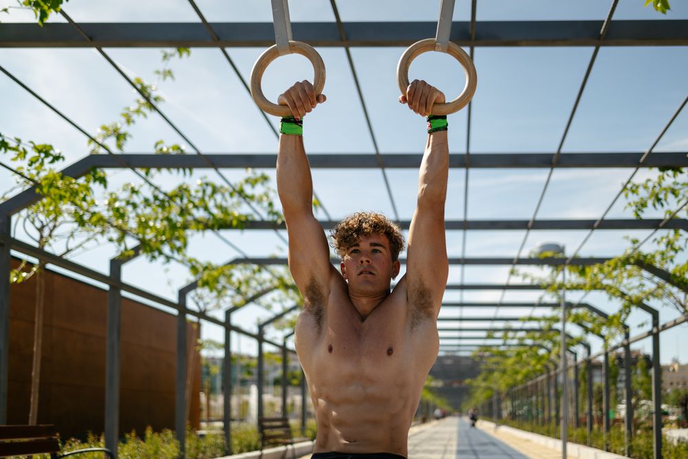 Strong young sportsman exercising with rings
