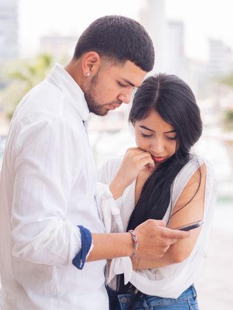 Man messaging on smartphone standing with woman