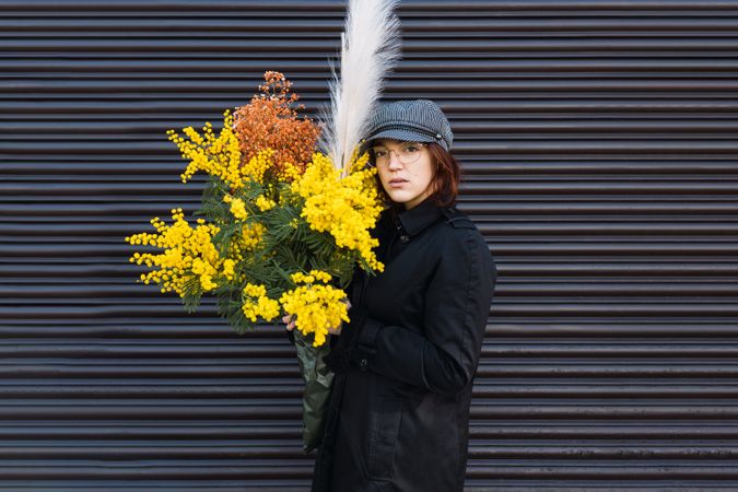 Woman with bouquet against gray wall