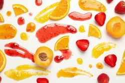 Apricot, strawberry, orange and jams on plain background