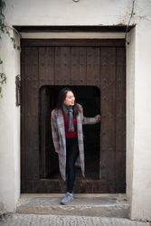 Content female tourist peering from small door of ancient building
