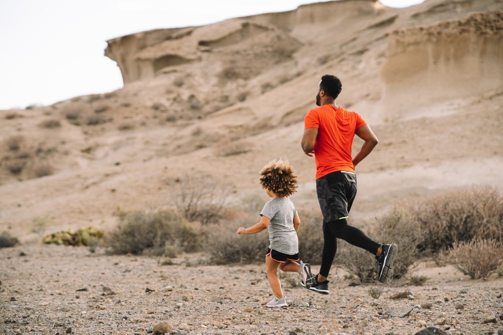 Black man jogging with toddler on nature