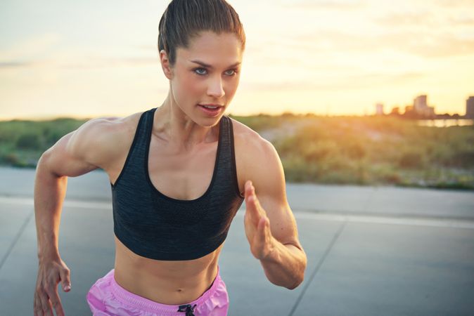 Muscular athletic woman running in morning light with tones abs and arms